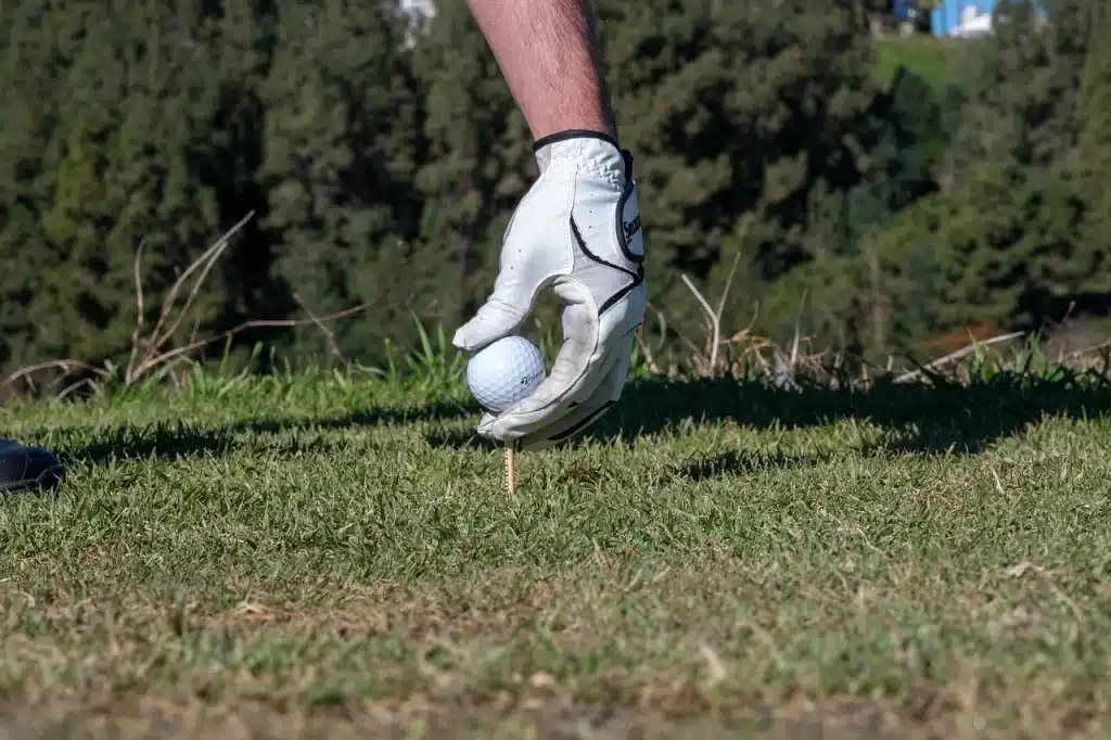 Osoba postavlja golf lopticu na tee