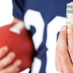 Igrač američkog nogometa drži novce u ruci (Kako se kladiti na igrače)