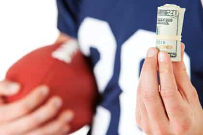 Igrač američkog nogometa drži novce u ruci (Kako se kladiti na igrače)