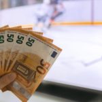 Osoba drži novčanice na hokej utakmici (kako se kladiti na hokej)