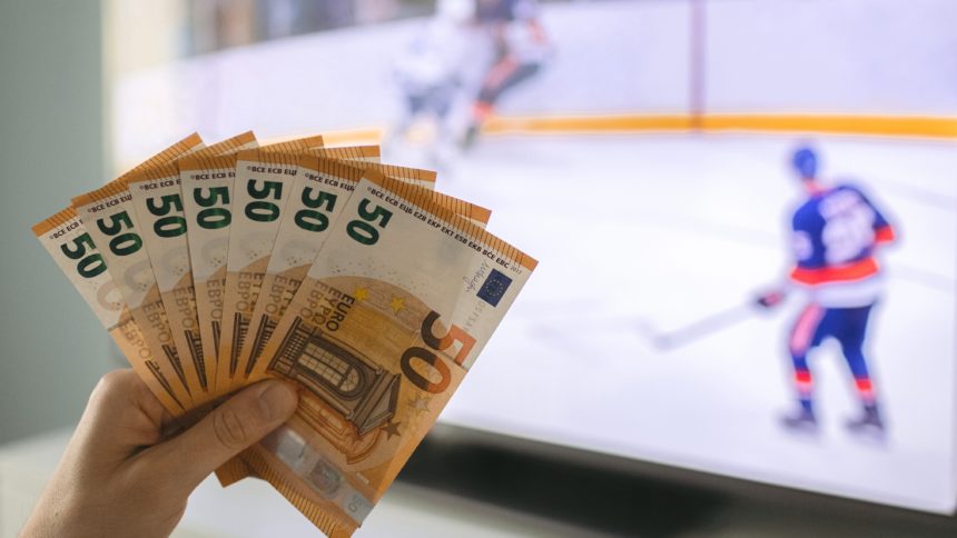 Osoba drži novčanice na hokej utakmici (kako se kladiti na hokej)
