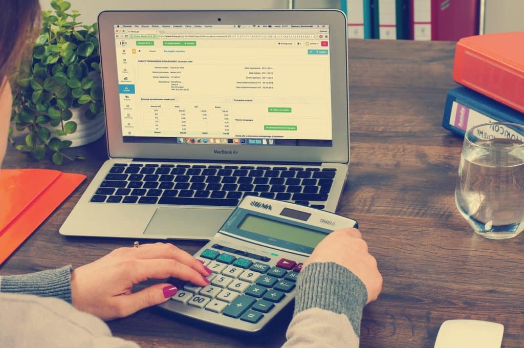 Žena koristi kalkulator ispred uključenog laptopa (kako kladionice plaćaju porez)