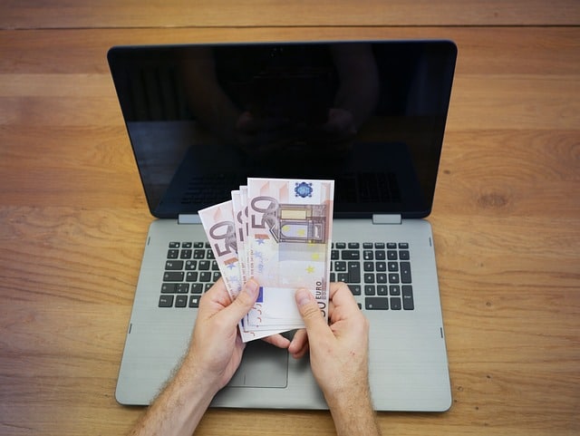 Osoba broji novce na laptopu (kako se kladiti online)